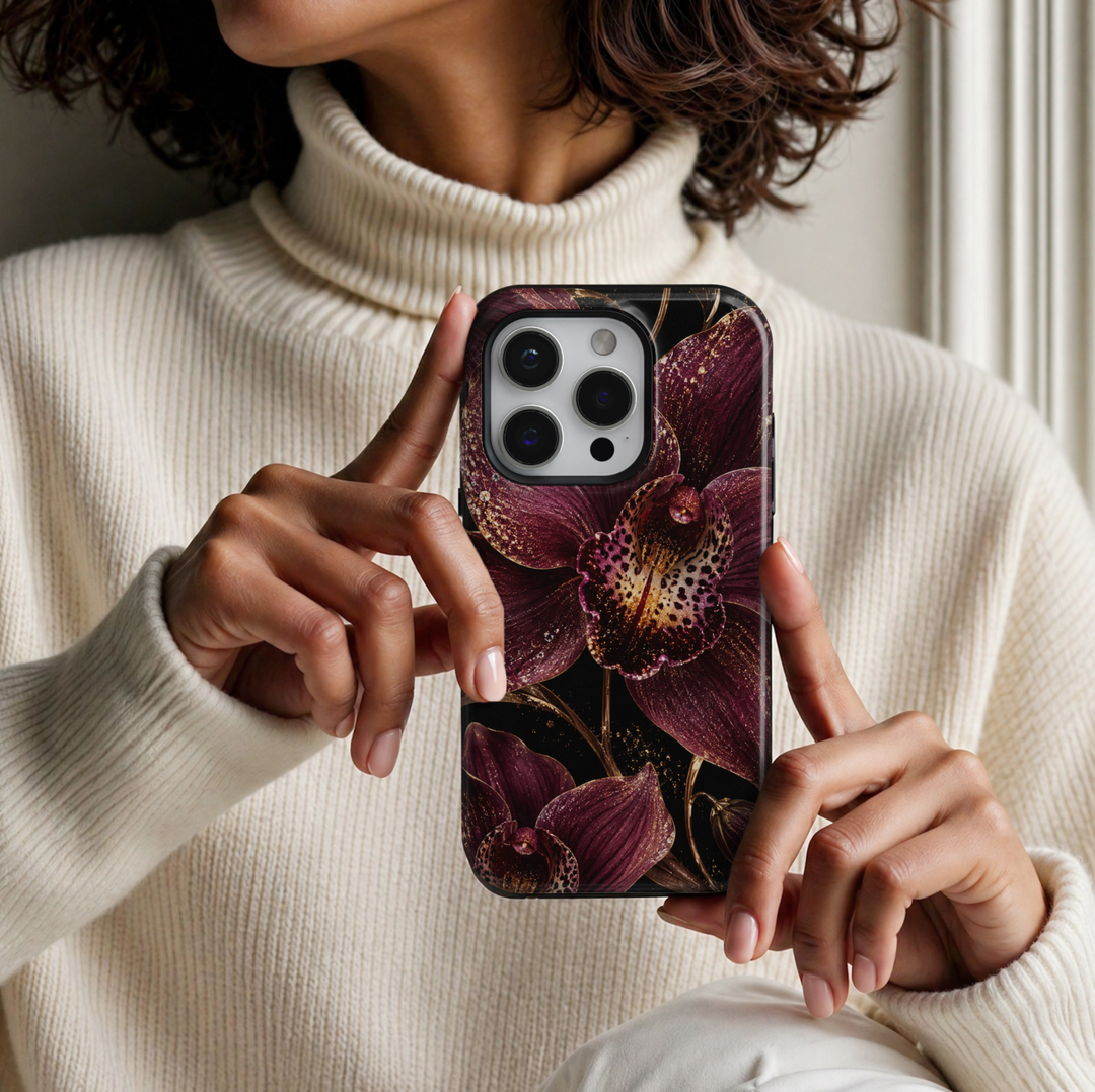 CASELIX Burgundy Orchid Luxe iPhone Tough MagSafe protective phone case featuring oversized deep burgundy and plum-purple orchids with intricate spotted petals, shimmering champagne-gold glitter effects, and delicate golden botanical stems against a dramatic black background. The luxurious floral design showcases rich wine-red orchid blossoms, sparkling jewel-inspired accents, and elegant metallic gold-inspired detailing for a sophisticated dark romantic aesthetic. Stylish burgundy orchid floral iPhone case