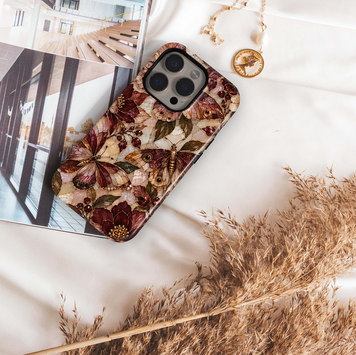 Cabernet Butterfly iPhone 18 Pro Max MagSafe case featuring stained-glass-inspired butterflies and moths in cabernet, burgundy, champagne and bronze with olive foliage and jewel-like berries over a pearlescent background, a luxurious tough iPhone 18 Pro butterfly phone case with MagSafe compatibility.