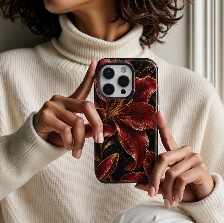 CASELIX Crimson Lily Luxe iPhone Tough MagSafe protective phone case featuring oversized deep crimson-red lilies with dramatic black-speckled petals, shimmering champagne-gold glitter effects, and elegant golden botanical stems against a rich jet-black background. The luxurious floral artwork showcases vibrant ruby-red and burgundy lily blossoms, intricate golden stamens, sparkling metallic-inspired accents, and beautifully detailed flower buds. Stylish red and black lily floral iPhone case with a glossy pr
