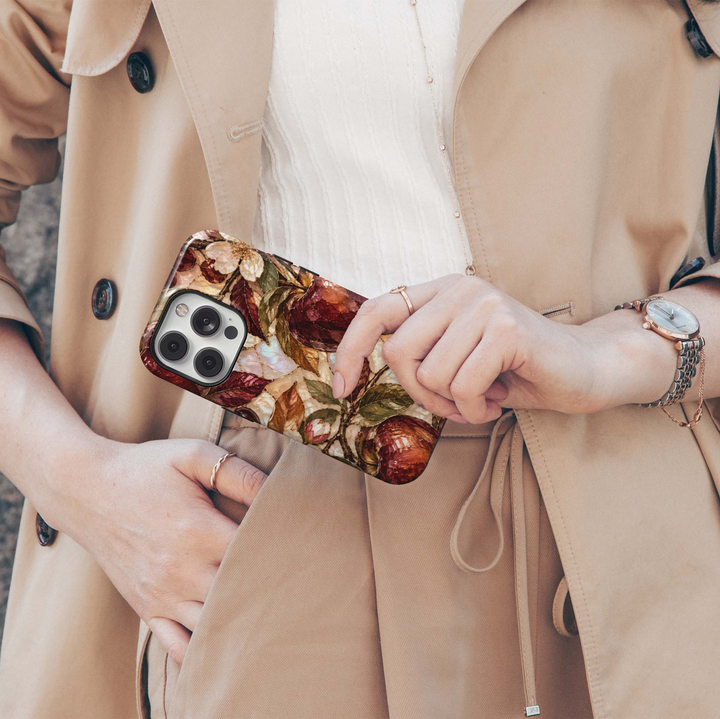 Garnet Orchard iPhone 18 Pro Max MagSafe case featuring jewel-toned burgundy and garnet orchard fruit with olive, bronze and copper leaves over a pearlescent ivory background, a luxurious stained-glass-inspired tough iPhone 18 Pro fall phone case with MagSafe compatibility.