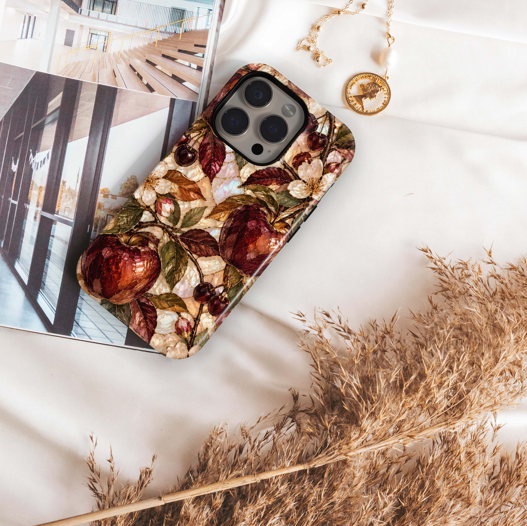 Garnet Orchard iPhone 18 Pro Max MagSafe case featuring jewel-toned burgundy and garnet orchard fruit with olive, bronze and copper leaves over a pearlescent ivory background, a luxurious stained-glass-inspired tough iPhone 18 Pro fall phone case with MagSafe compatibility.