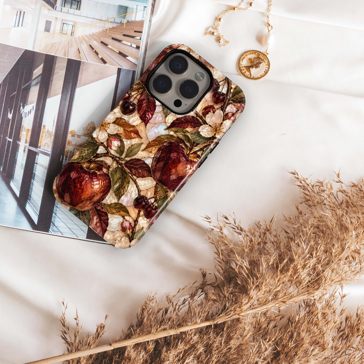 Garnet Orchard iPhone 18 Pro Max MagSafe case featuring jewel-toned burgundy and garnet orchard fruit with olive, bronze and copper leaves over a pearlescent ivory background, a luxurious stained-glass-inspired tough iPhone 18 Pro fall phone case with MagSafe compatibility.