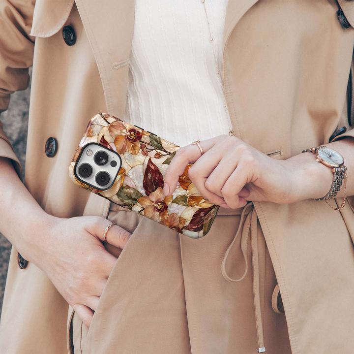 Amber Orchid iPhone 18 Pro Max MagSafe case featuring pearlescent orchids and botanical blooms in amber, champagne, caramel and ivory with burgundy and olive leaves, a luxurious stained-glass-inspired tough iPhone 18 Pro floral phone case with MagSafe compatibility.