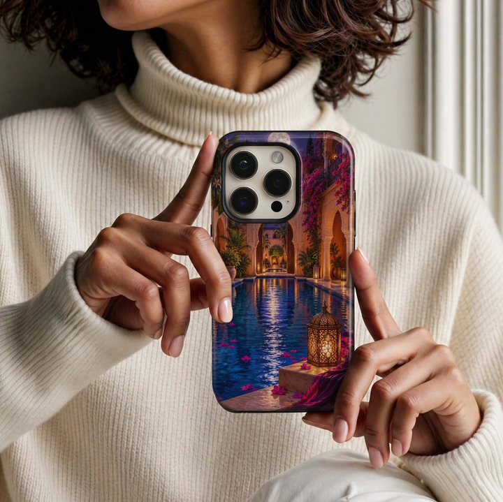 Moonwater Riad Tough iPhone Case featuring a moonlit Moroccan-inspired courtyard with a deep blue reflecting pool, ornate glowing lanterns, bougainvillea, arches and rich magenta textiles.