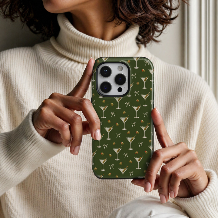 CASELIX Olive Hour iPhone 18 Pro Max tough phone case featuring a deep olive-green background with repeating dirty martini cocktail glasses, green olives with red pimentos, delicate ivory ribbon bows, and miniature olive illustrations. Chic glossy printed phone case for women with a minimalist cocktail-inspired aesthetic and trendy olive-green design.