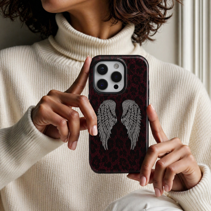 CASELIX Burgundy Angel Wings iPhone Tough MagSafe protective phone case featuring elegant silver rhinestone-inspired angel wings against a luxurious deep burgundy and black leopard print background. The striking design showcases intricately detailed crystal-like feathered wings with shimmering diamond-inspired accents, contrasting beautifully with rich wine-red animal print textures. Stylish burgundy leopard print iPhone case with sparkling silver angel wings, a glossy printed finish, glamorous gothic celes