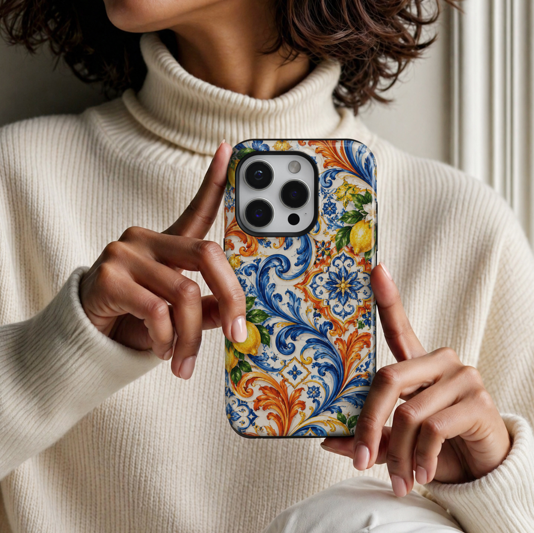 CASELIX Amalfi Citrus Tiles iPhone Tough MagSafe protective phone case featuring a vibrant Italian Mediterranean-inspired ceramic tile pattern adorned with golden-yellow lemons, intricate cobalt-blue scrollwork, and elegant orange botanical flourishes against a creamy ivory background. The captivating design showcases beautifully illustrated ripe lemons surrounded by lush emerald-green leaves and delicate white citrus blossoms with golden centers. Ornate sapphire-blue acanthus leaves, sweeping baroque-inspi