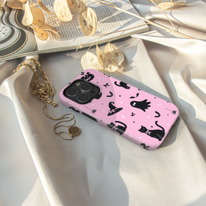 Pink Halloween iPhone case with black cats, ghosts, witch hats, bats, pumpkins, bows, spiders and paw prints.