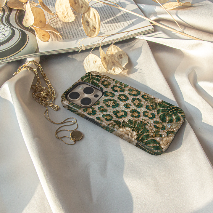 Luxury iPhone case featuring emerald green leopard print, tropical monstera leaves, ivory roses, pearls, and gold mosaic artwork.