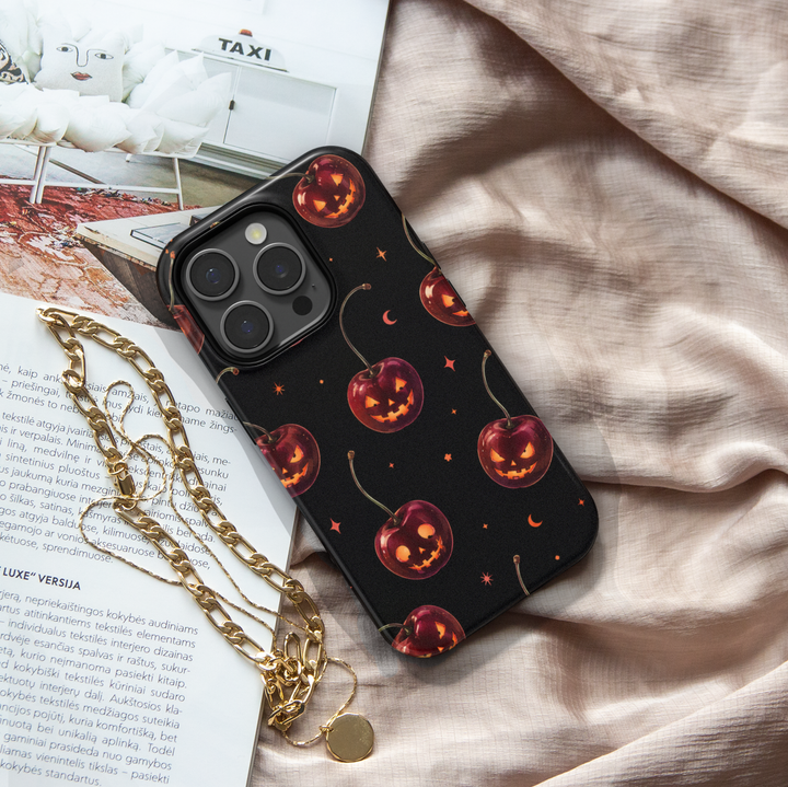 Black Halloween iPhone case with cherry red jack-o-lantern pumpkins, glowing faces, crescent moons and stars.