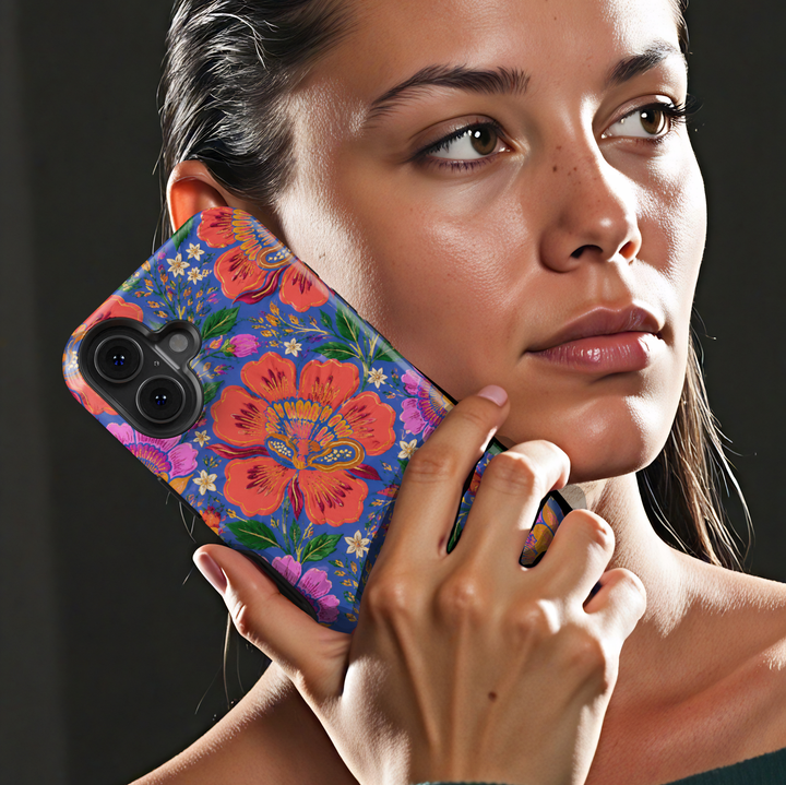 Electric Bloom iPhone case featuring vibrant coral, pink and orange flowers with green leaves on a cobalt blue background.