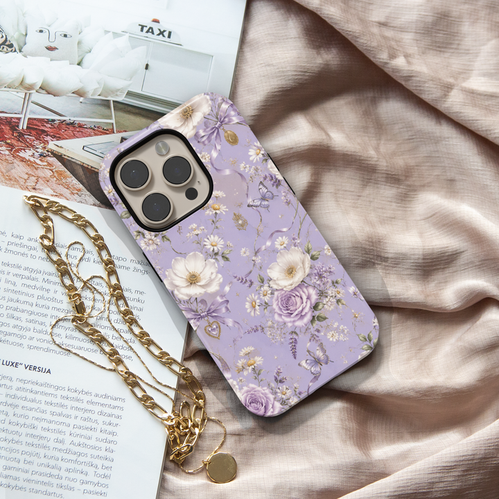 Lavender Reverie iPhone case with purple and ivory flowers, butterflies, lavender bows and vintage heart charms on a lilac background.