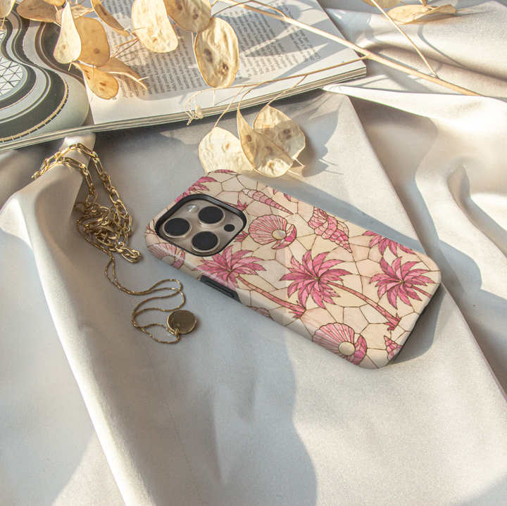 Pink tropical iPhone case featuring palm trees, seashells, pearls, and a soft coastal mosaic design.
