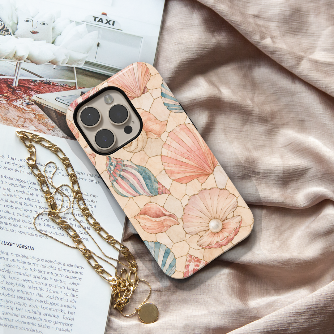 Pastel seashell iPhone case featuring pink scallop shells, spiral shells, pearl accents, and a soft coastal beach design.