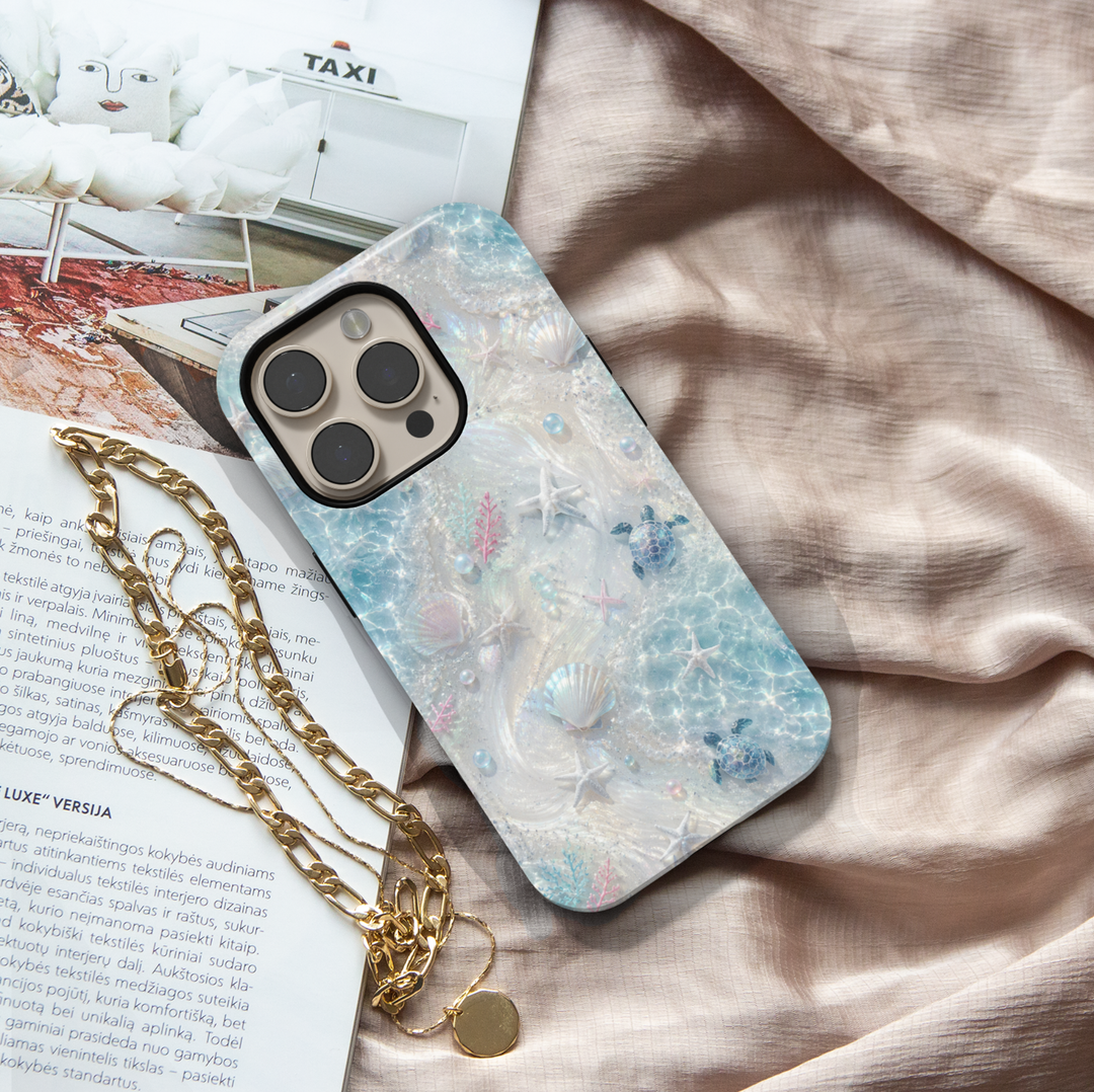 Sea turtle iPhone case featuring seashells, starfish, coral accents, and shimmering ocean waves in soft aqua tones.