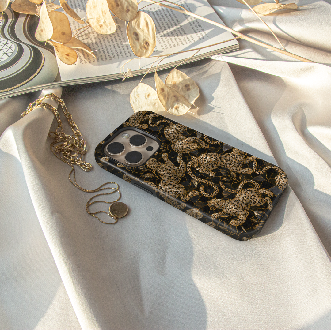 Golden Prowl iPhone case with ornate gold leopards, botanical details and a luxurious black background.