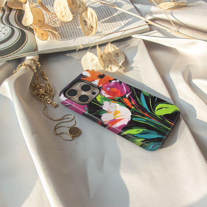 Modern abstract floral iPhone case featuring vibrant colorful flowers with white blossoms on a dark artistic background.
