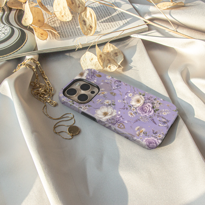 Lavender Reverie iPhone case with purple and ivory flowers, butterflies, lavender bows and vintage heart charms on a lilac background.