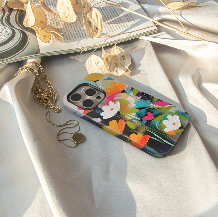 Modern abstract floral iPhone case featuring vibrant colorful flowers with white blossoms on a dark artistic background.