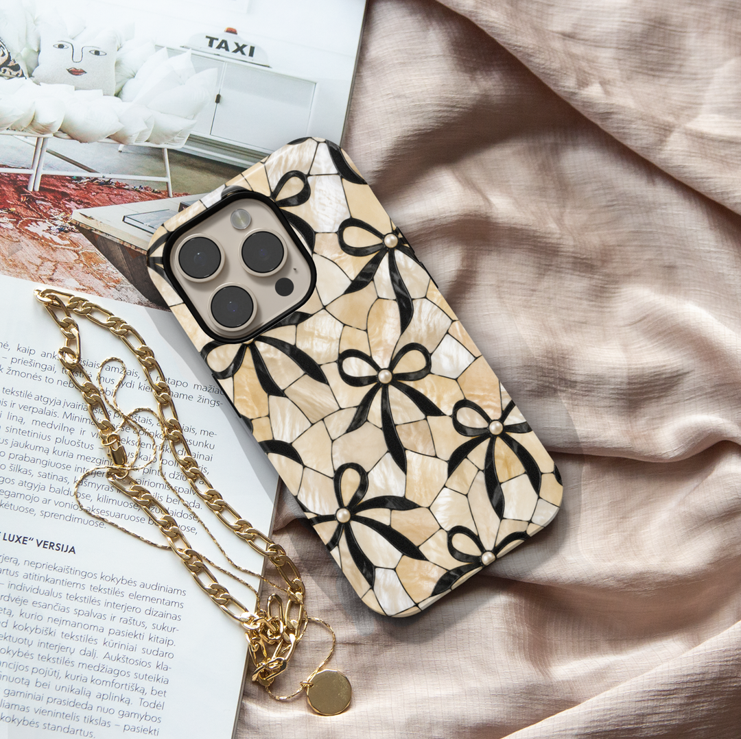 Ivory mosaic iPhone 17 Pro Max case with black bow pattern and pearl accents in a classy aesthetic design.