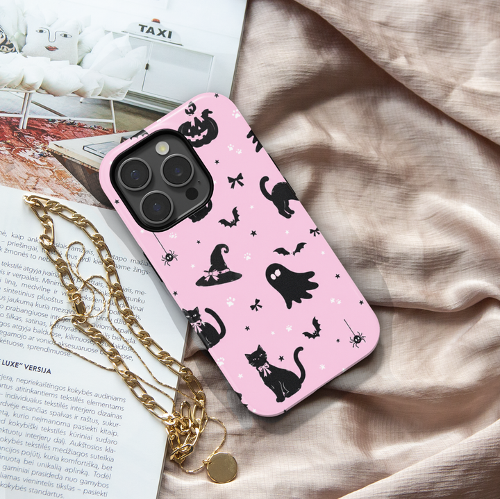 Pink Halloween iPhone case with black cats, ghosts, witch hats, bats, pumpkins, bows, spiders and paw prints.