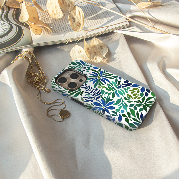 Blue and green botanical iPhone case featuring floral blooms and leafy watercolor-inspired artwork on a white background.