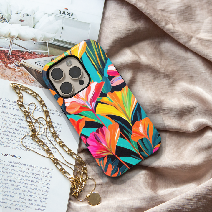 Colorful tropical floral iPhone case featuring vibrant orange, pink, yellow, and teal flowers on a dark botanical background.