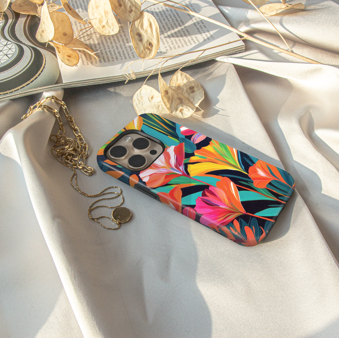 Colorful tropical floral iPhone case featuring vibrant orange, pink, yellow, and teal flowers on a dark botanical background.