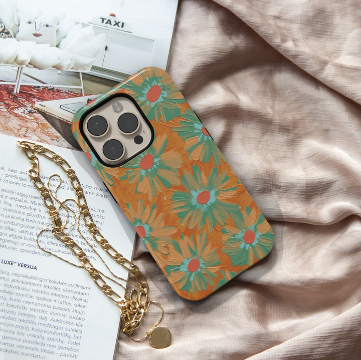 Hand-painted retro floral iPhone case featuring teal daisies on a warm copper background with textured brushstroke artwork.