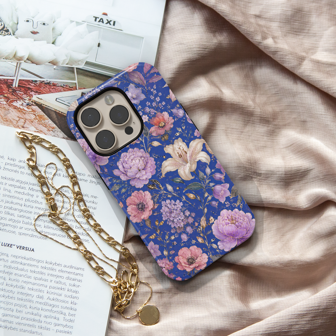 Electric Bloom iPhone case featuring vibrant coral, pink and orange flowers with green leaves on a cobalt blue background.
