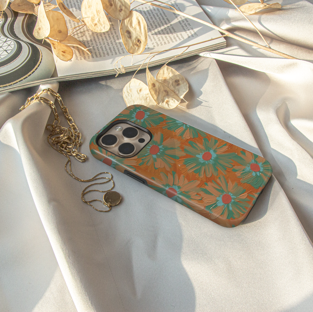 Hand-painted retro floral iPhone case featuring teal daisies on a warm copper background with textured brushstroke artwork.