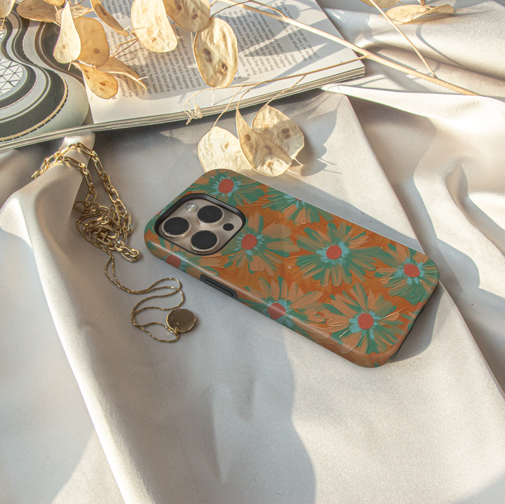 Hand-painted retro floral iPhone case featuring teal daisies on a warm copper background with textured brushstroke artwork.