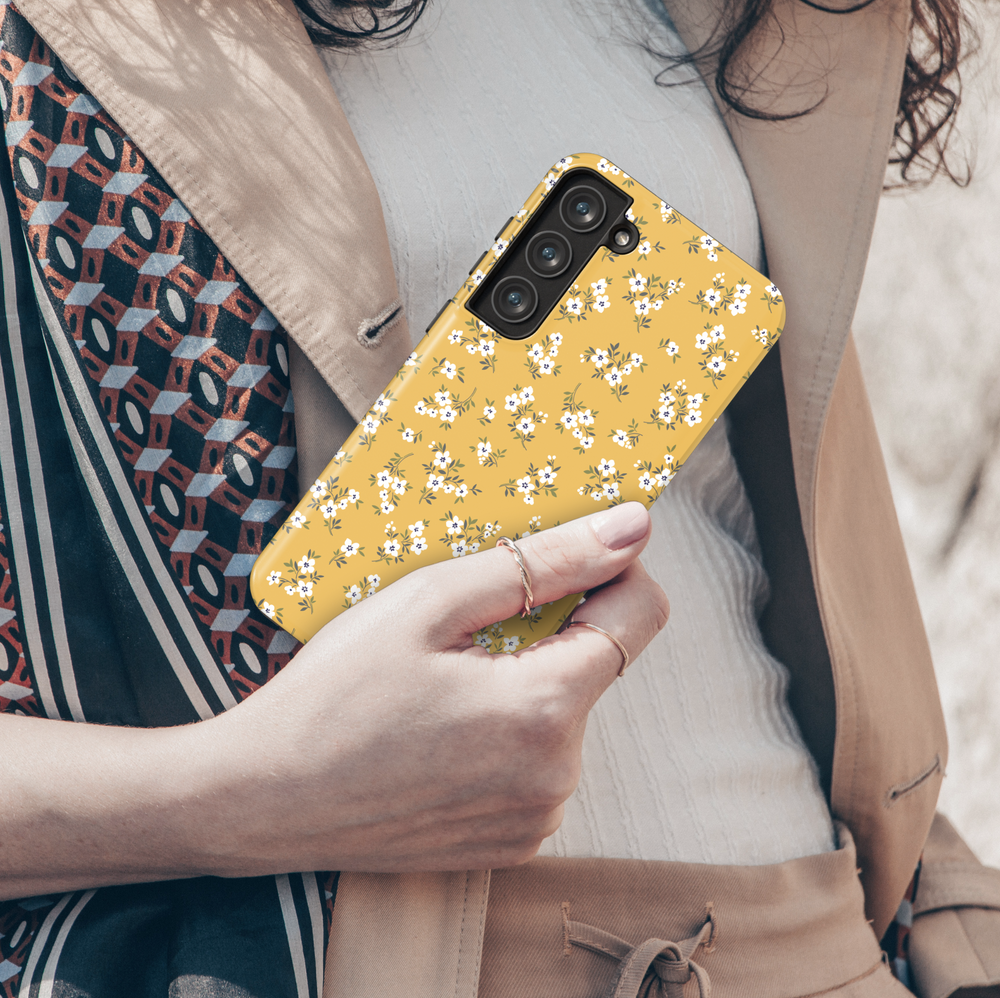 Add a pop of sunshine to your phone with this mustard yellow Galaxy case. Designed with petite white flowers and green leaves, it’s a fun and vibrant accessory for everyday style.