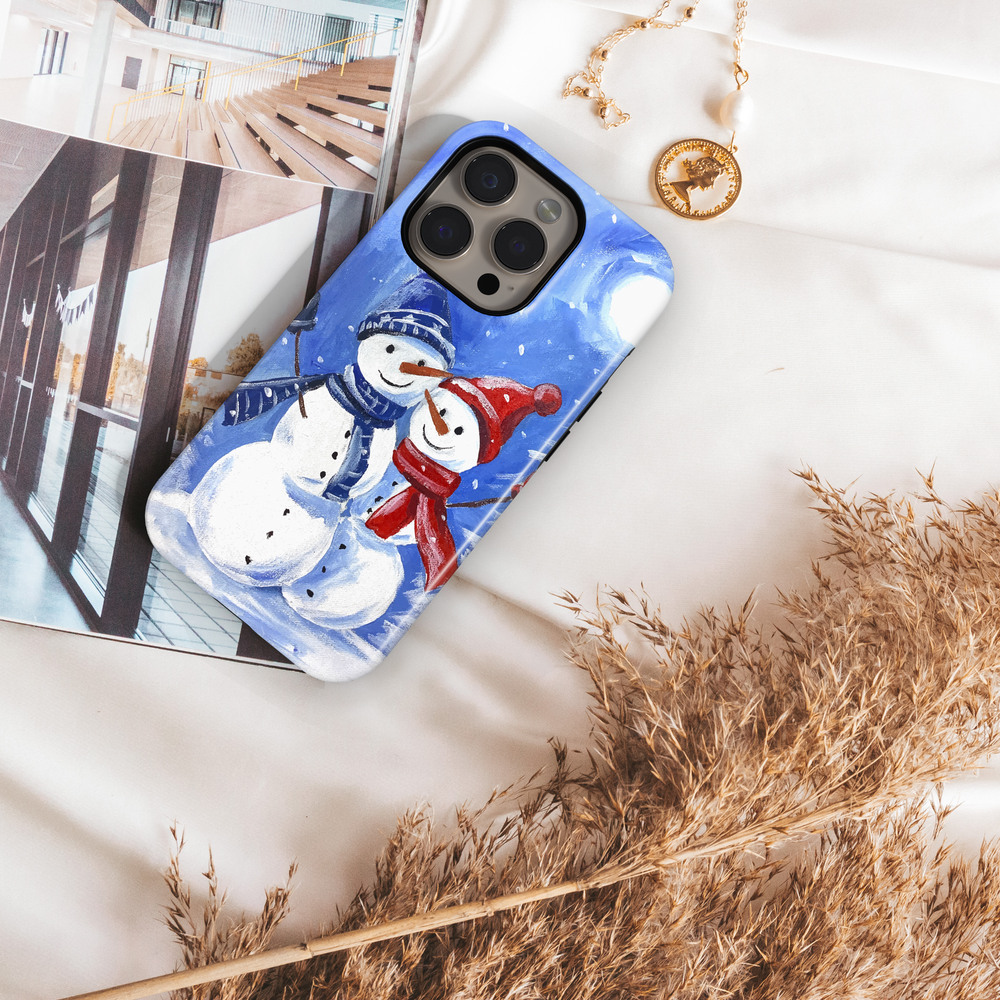 Hand-painted snowman couple phone case with blue winter background, red and blue hats and scarves, snowy holiday artwork