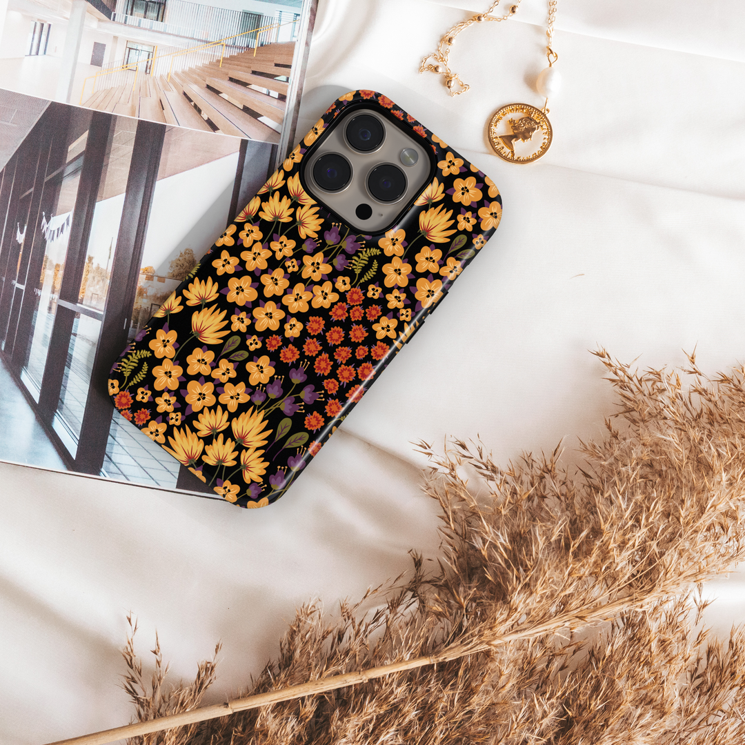 Autumn floral phone case with yellow, orange, and purple flowers on black background, fall aesthetic design