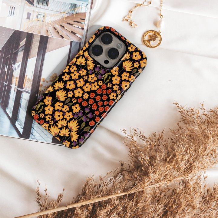 Autumn floral phone case with yellow, orange, and purple flowers on black background, fall aesthetic design